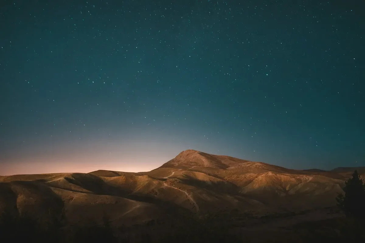 A starry night sky over desert mountains at dusk, evoking the stars and sand of Genesis 22:17