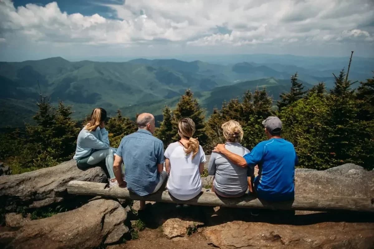 A family sitting together on a mountain overlook, taking in the view side by side