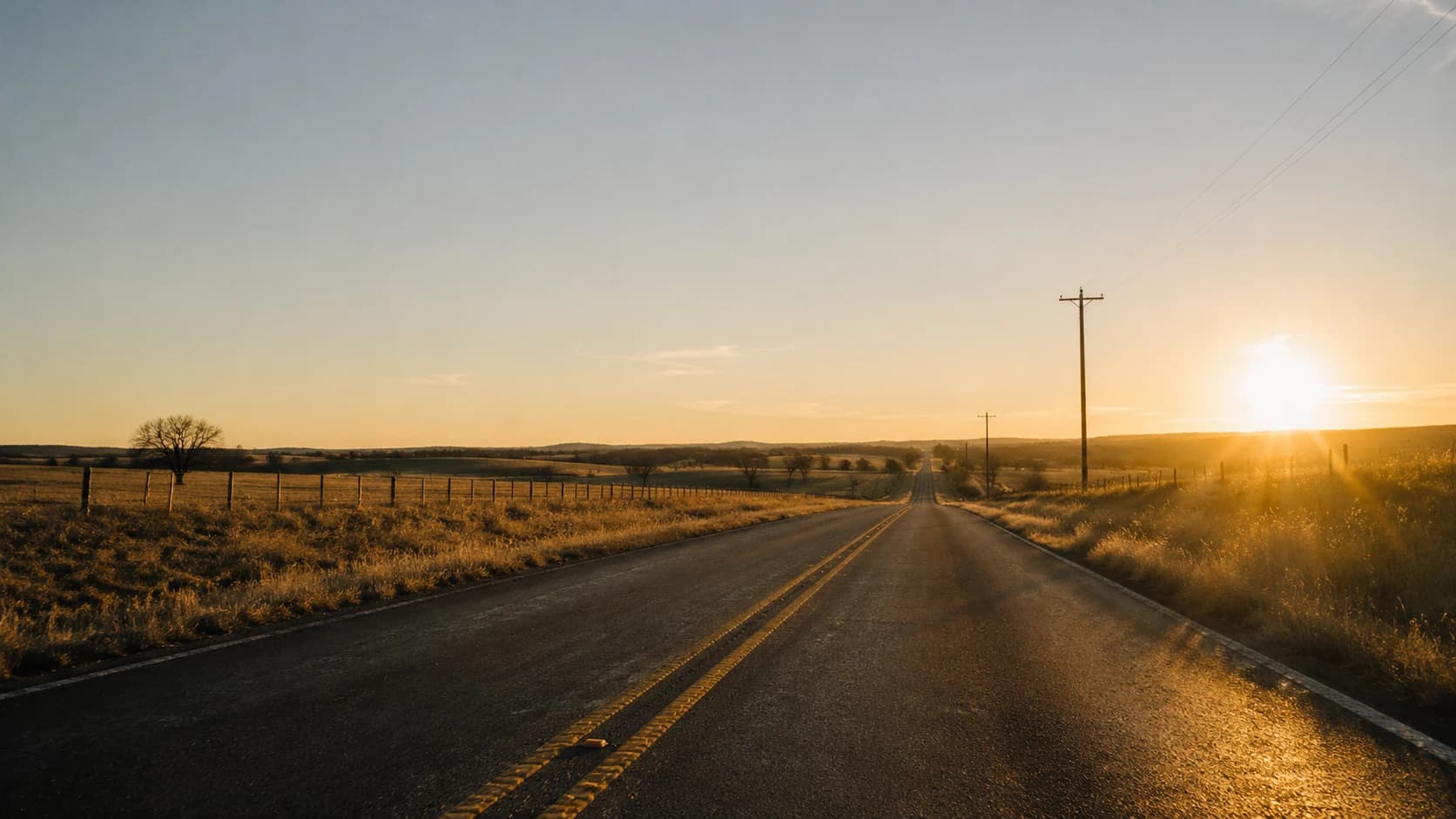 A quiet country road through Texas ranchland at golden hour