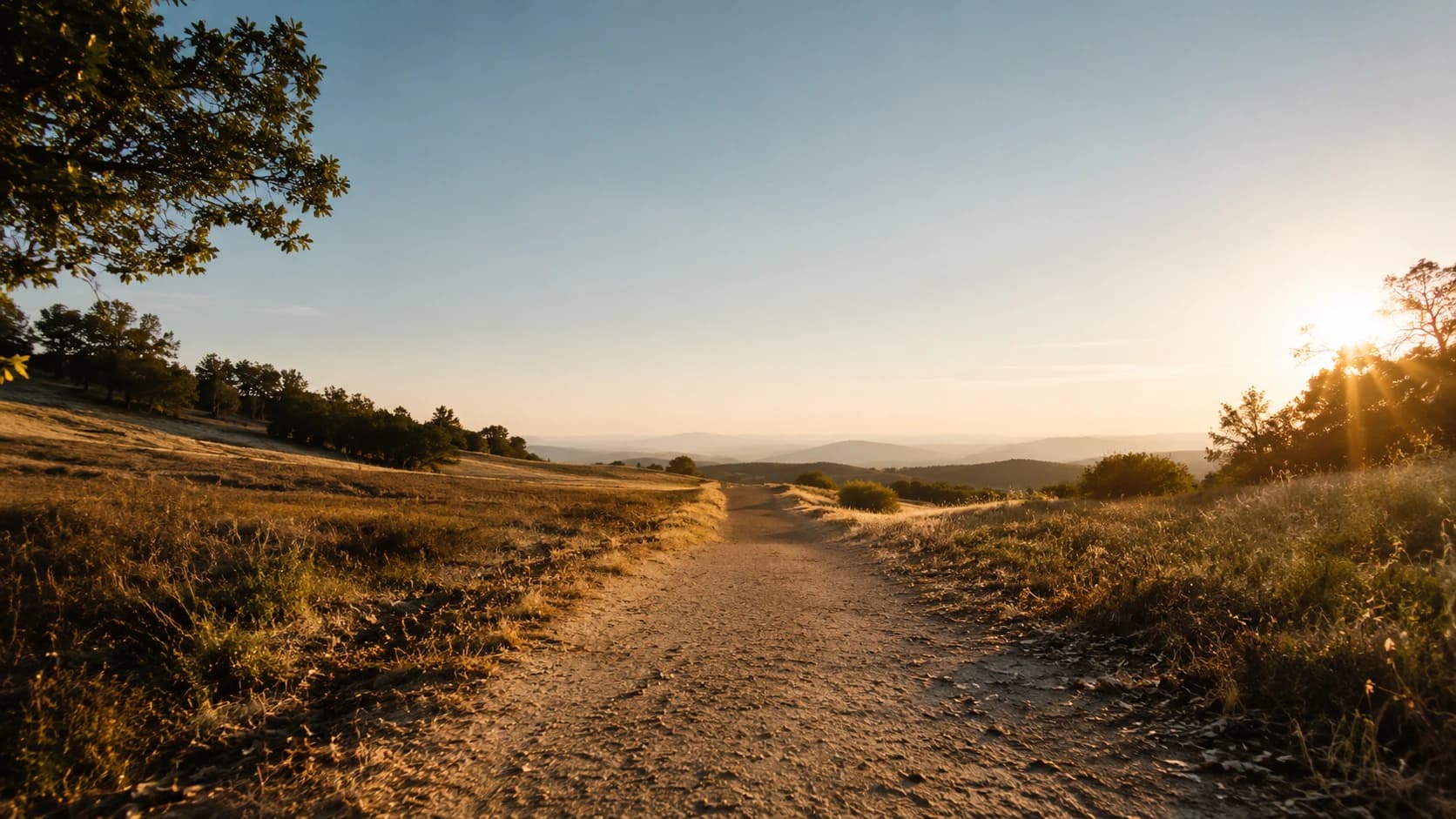 A single trail continuing forward through open countryside at golden hour