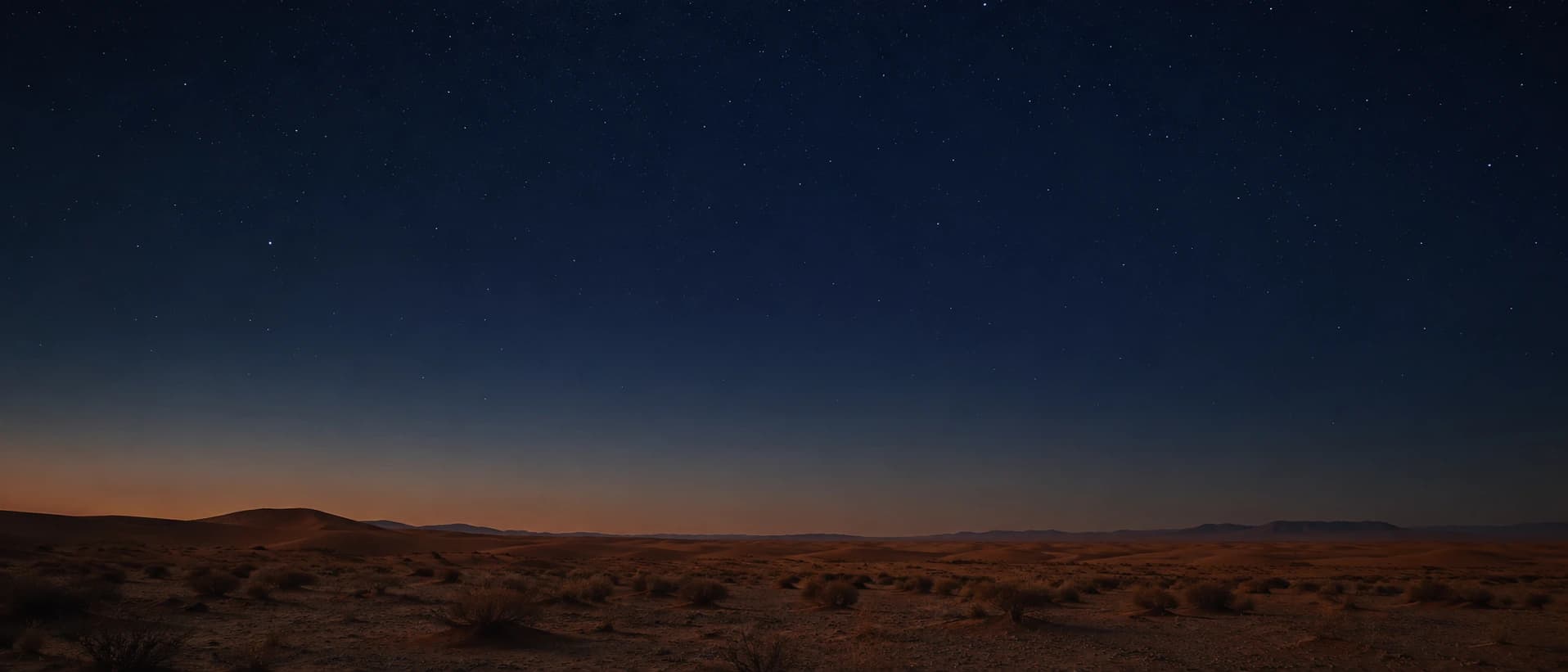 Stars over a quiet desert landscape at night